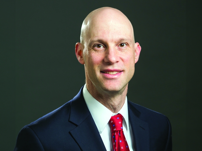 Headshot of Daniel Goldstein. He's wearing a dark suit, red tie, and white button up shirt.