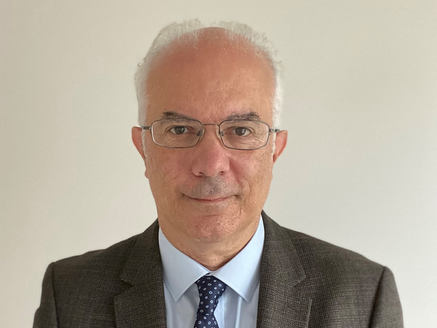 Smiling headshot of Cem Akin, M.D. He has short gray hair and glasses and is wearing a brown jacket and blue tie with white dots.