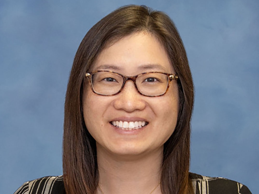 Smiling portrait of Eliza Tsou, Ph.D. She has long dark hair and glasses and is wearing a plaid top.