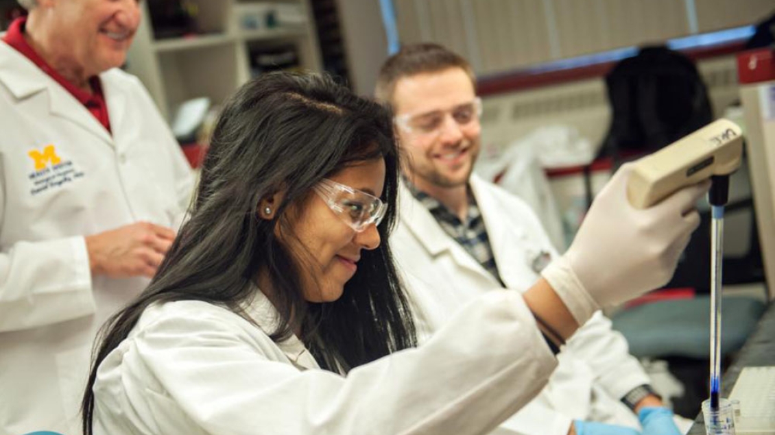 Three people in lab coats working together in a lab